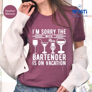 May include: A heather maroon t-shirt with the text "I'm sorry the nice bartender is on vacation" in white. The text is surrounded by four white silhouettes of different types of glasses.