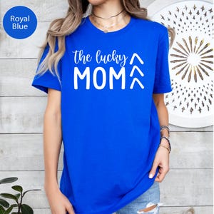 May include: Royal blue t-shirt with the text "the lucky MOM" in white script and block letters. The shirt has short sleeves and a crew neck. The text is centered on the front of the shirt.