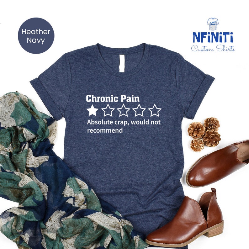 May include: A heather navy blue t-shirt with a white graphic that says "Chronic Pain" and has a one-star rating with the text "Absolute crap, would not recommend".