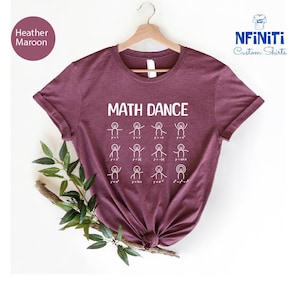 Könnte beinhalten: Heather-Maroon-T-Shirt mit dem weißen Schriftzug "MATH DANCE" und Strichmännchen, die mathematische Gleichungen darstellen. Das Shirt hängt an einem Holzkleiderbügel. Der Markenname "NFiniTi Custom Shirts" ist oben rechts zu sehen.