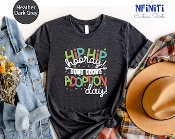 May include: Heather dark grey t-shirt with the text "Hip Hip Hooray! It's Always Adoption Day!" in colorful letters with confetti around the text.
