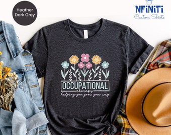May include: Heather dark grey t-shirt with a floral design and the text "Occupational Therapy - helping you grow your way".
