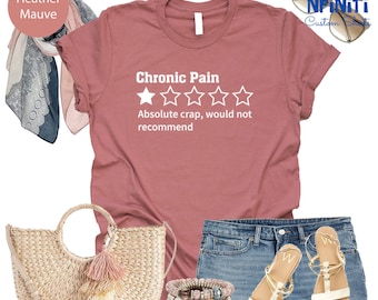 Può includere: T-shirt color malva heather con il testo "Chronic Pain" e una valutazione di una stella. Il testo sotto la valutazione dice "Absolute crap, would not recommend".