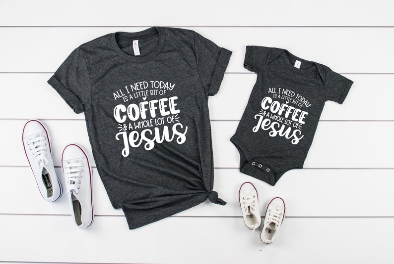 May include: Dark gray t-shirt and onesie set with the text "ALL I NEED TODAY IS A LITTLE BIT OF COFFEE & A WHOLE LOT OF JESUS" in white. White sneakers with red trim are also in the image. The set is a matching outfit.