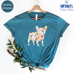 Peut inclure: Un t-shirt bleu sarcelle avec un motif floral &agrave; l'int&eacute;rieur de la silhouette d'un bouledogue fran&ccedil;ais. Le texte "NFINITI Custom Shirts" est dans le coin sup&eacute;rieur droit de l'image.