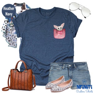 May include: Heather navy t-shirt with a pocket featuring a watercolour illustration of a fennec fox. The shirt is paired with denim shorts, embellished flats, a brown handbag, a patterned scarf, and aviator sunglasses. The text "NFINITI Custom Shirts" is visible.