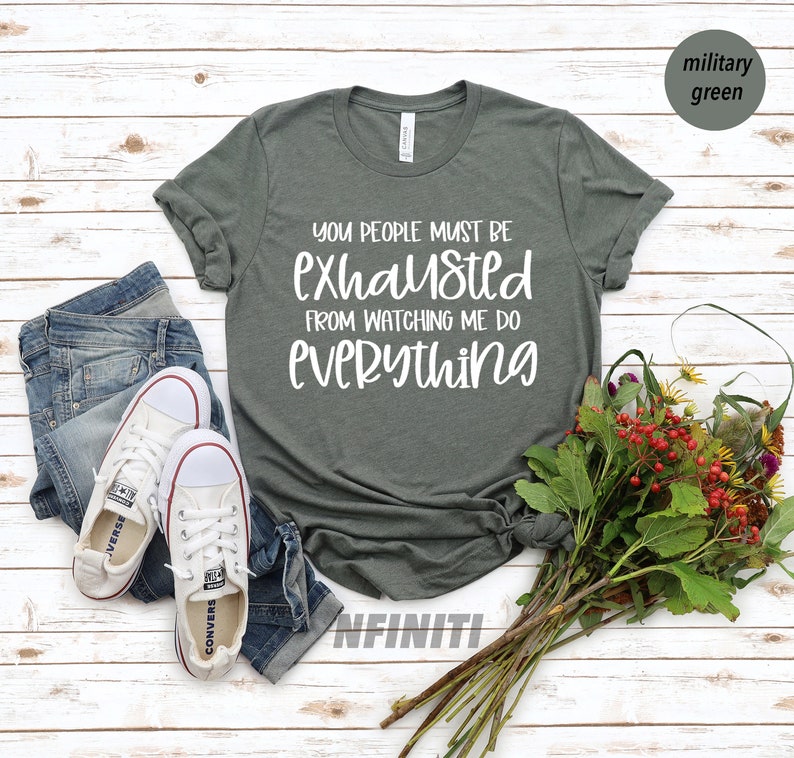 May include: A dark green t-shirt with white text that reads "You people must be exhausted from watching me do everything".