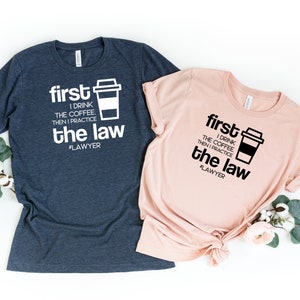 以下が含まれることがあります： コーヒーカップのグラフィックと「first I drink the coffee then I practice the law #LAWYER」というテキストが書かれたTシャツ2枚。