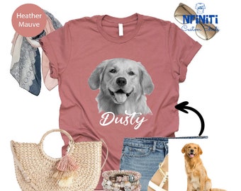 May include: A heather mauve t-shirt featuring a black and white photograph of a golden retriever dog with the name "Dusty" printed beneath the image. The shirt is styled with blue denim shorts, a straw bag with a tassel, and a pair of white sandals.