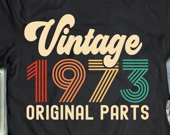 May include: A black t-shirt with a vintage design featuring the year 1973 in colorful stripes and the text "Vintage 1973 Original Parts".