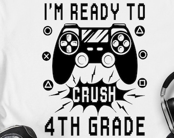 May include: A white t-shirt with a black graphic design of a video game controller with the text "I'm Ready To Crush 4th Grade".