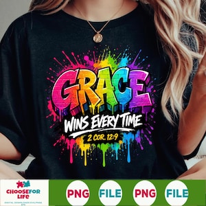 May include: A black t-shirt featuring a vibrant, multi-colored paint splatter design. The word GRACE is written in large, brick-textured letters, followed by the white text WINS EVERY TIME and the reference 2 COR. 12:9 in a bold, yellow font.
