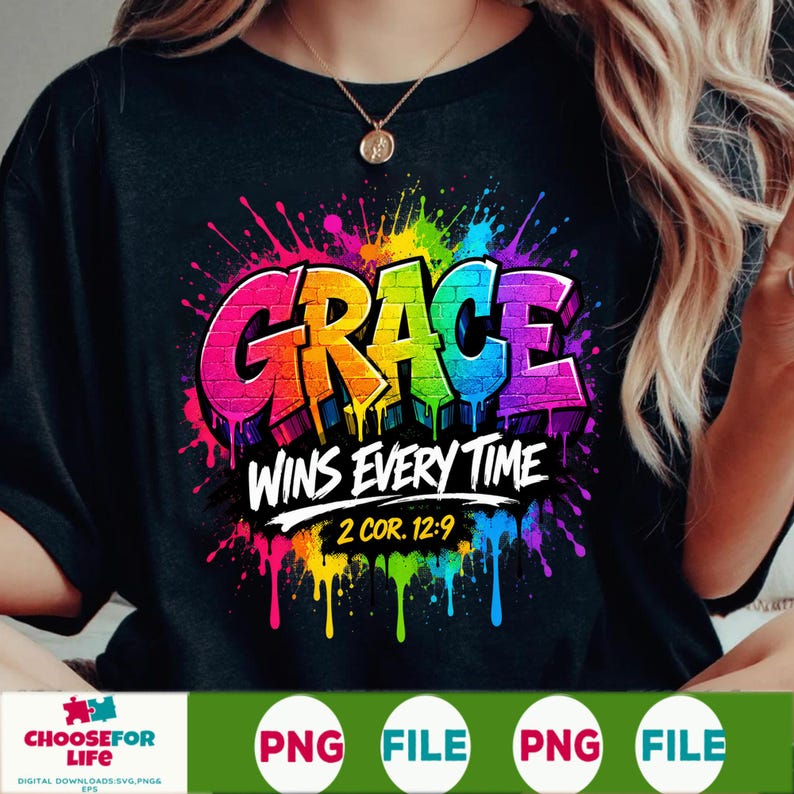 May include: A black t-shirt featuring a vibrant, multi-colored paint splatter design. The word GRACE is written in large, brick-textured letters, followed by the white text WINS EVERY TIME and the reference 2 COR. 12:9 in a bold, yellow font.
