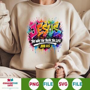 May include: A beige crewneck sweatshirt featuring a colorful graffiti-style graphic that reads JESUS THE WAY, THE TRUTH, THE LIFE and JOHN 14:6. The design includes vibrant paint splatters in pink, blue, yellow, and green surrounding the text.