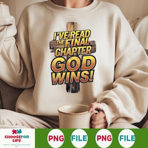 May include: Cream-colored sweatshirt with the text "I'VE READ THE FINAL CHAPTER GOD WINS!" in a cross design. The text is in yellow and black, with a wooden cross background. A person is holding a beige mug.