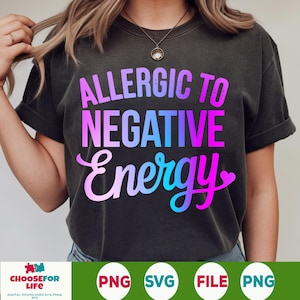 May include: Dark gray t-shirt with the text "ALLERGIC TO NEGATIVE ENERGY" in a gradient of pink, purple, and blue. The shirt has short sleeves and a relaxed fit. The bottom of the shirt has the words "CHOOSE FOR LIFE" and the file types PNG, SVG, and FILE.