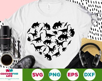 May include: A white t-shirt with a black silhouette of a heart filled with dinosaurs. The design includes various dinosaur shapes and sizes, creating a playful and whimsical pattern.
