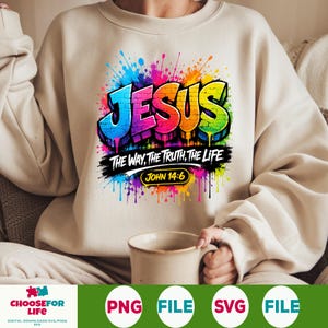 May include: A beige crewneck sweatshirt featuring a colorful graffiti-style graphic that reads JESUS THE WAY, THE TRUTH, THE LIFE and JOHN 14:6. The design includes vibrant paint splatters in blue, purple, red, orange, yellow, and green.