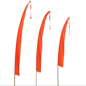 May include: Three orange fabric flags on poles, each with a pointed tip and a tassel at the end. The flags are arranged in a row, with the largest flag on the left and the smallest flag on the right.