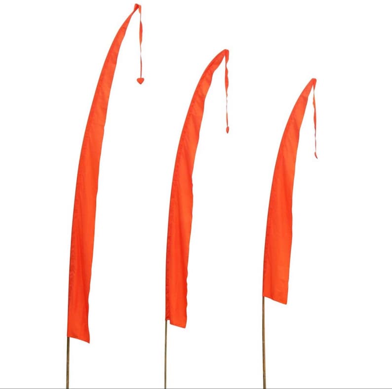 May include: Three orange fabric flags on poles, each with a pointed tip and a tassel at the end. The flags are arranged in a row, with the largest flag on the left and the smallest flag on the right.
