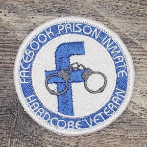 May include: Embroidered patch with a blue and white design. The patch features the Facebook logo with handcuffs and the text "FACEBOOK PRISON INMATE HARDCORE VETERAN" in a circular pattern around the logo.