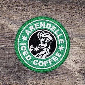 May include: A green and white embroidered patch with the text "Arendelle Iced Coffee" and a cartoon image of Elsa from the movie Frozen.
