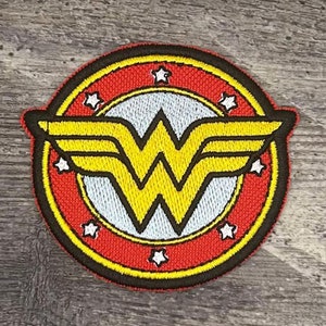 May include: A red, yellow, and white embroidered Wonder Woman logo patch with a circle of white stars around the outside.