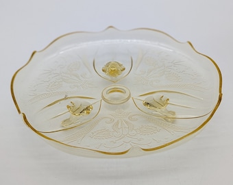 以下が含まれることがあります： 金色の縁取りとエッチングされた花の模様が施された透明なガラス製のサービングディッシュ。このディッシュは3本の脚と中央の台座を持っています。