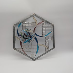 Puede incluir: Una ventana de vitral hexagonal con fondo blanco y un diseño colorido en el centro. El diseño presenta piezas de vidrio azul, rojo, amarillo y verde.