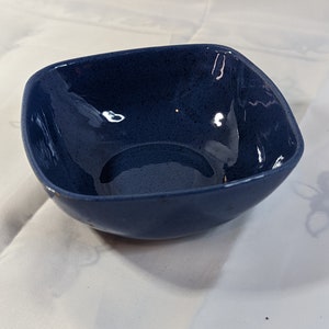Peut inclure: Un bol carré en céramique bleu foncé avec un glaçage moucheté.