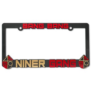 Könnte beinhalten: Schwarzer Kennzeichenrahmen mit den Worten "BANG BANG" in roten Buchstaben oben und "NINER GANG" in goldenen und roten Buchstaben unten. Der Rahmen hat auf jeder Seite ein 49ers-Logo.