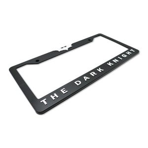 May include: Black license plate frame with the words "THE DARK KNIGHT" in white lettering. The Batman logo is visible in white on the top left corner. The frame is rectangular and has pre-drilled holes for mounting.