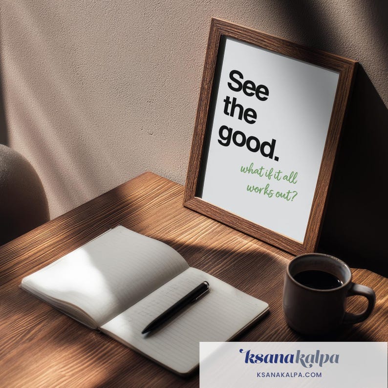 May include: A framed print featuring the black text See the good. and the green text what if it all works out? displayed in a brown wooden frame next to an open notebook with a black pen and a dark brown ceramic mug of coffee.
