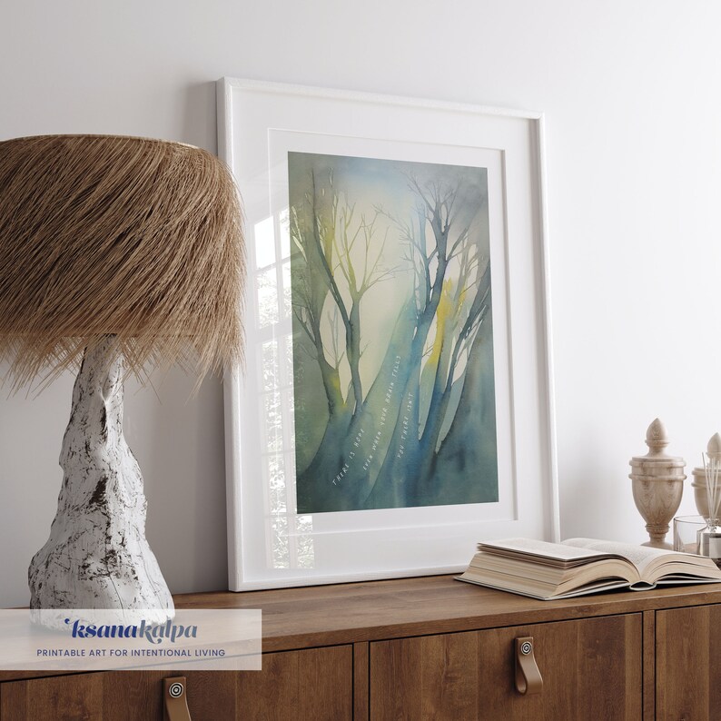 May include: A framed watercolor painting of a forest scene with trees and a blue and green color scheme. The text "There is still magic in the air" is written in white on the painting.