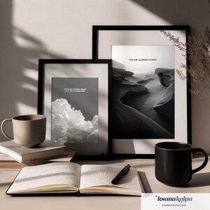 May include: Two black-framed wall art prints featuring monochrome landscapes and clouds with the text IF IT'S OUT OF YOUR HANDS LET IT OUT OF YOUR MIND and YOU ARE ALLOWED TO SHIFT, accompanied by two ceramic mugs, a stack of books, and an open notebook.