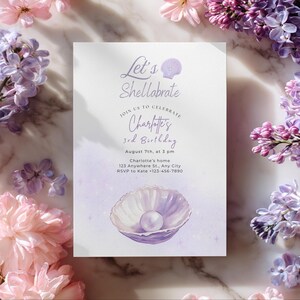 Op de afbeelding: Een lila-thema verjaardagsuitnodiging met de tekst "Let's Shellabrate" en "Charlotte's 3e verjaardag". De uitnodiging heeft een schelpgrafiek met een parel en is omgeven door lila en roze bloemen.