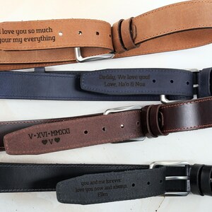 May include: Four leather belts in tan, navy blue, dark brown, and black, each featuring a silver-toned metal buckle and a personalised laser-engraved message on the strap. The engravings include text such as I love you so much, V-XVI-MMXXI, and more.