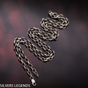 May include: A silver chain necklace with a lobster clasp. The chain is made of oval links.