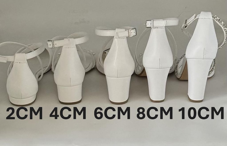 以下が含まれることがあります： 2cm、4cm、6cm、8cm、10cmと表示された、異なるヒール高さの白いヒールサンダルが5足あります。