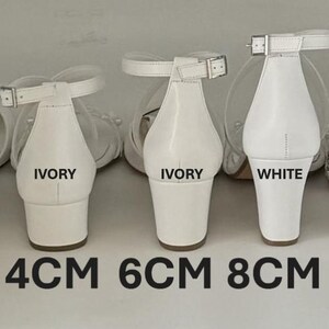Puede incluir: Tres pares de sandalias blancas de tac&oacute;n con correas de tobillo ajustables. Las sandalias est&aacute;n etiquetadas como "IVORY" y "WHITE" y tienen tacones de 4 cm, 6 cm y 8 cm.