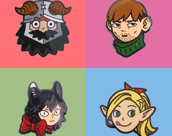 May include: Four enamel pins with cartoon character designs. The pins feature a Viking, a man with a green turtleneck, a cat-eared character with a red bow, and a blonde elf with a red bow. Each pin has a different colored background.