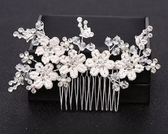 May include: Silver hair comb with a floral design. The comb is decorated with white pearl-like beads and clear rhinestones. The comb has a row of teeth on the bottom.