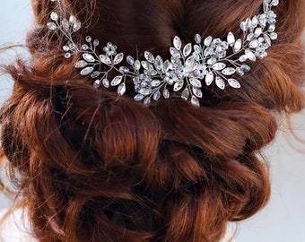 May include: Silver bridal hair comb with a delicate floral design featuring crystal rhinestones. The comb is perfect for adding a touch of sparkle to any hairstyle.