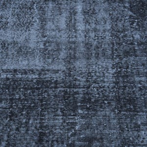 May include: A rectangular area rug featuring a distressed, weathered texture in shades of deep charcoal, slate gray, and faded black. The surface displays a dense, woven grid pattern with uneven color distribution, creating a worn, aged appearance.