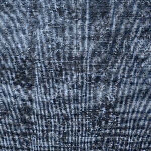 May include: A woven textile rug featuring a dense, grid-like pattern in shades of dark charcoal black and muted slate blue. The surface displays a distressed, weathered appearance with uneven color distribution across the entire fabric weave.