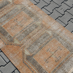 K&ouml;nnte beinhalten: Ein Vintage-L&auml;ufer mit geometrischem Muster in Braun-, Beige- und Wei&szlig;t&ouml;nen. Der Teppich hat einen Used-Look und ist perfekt, um jedem Raum einen Hauch von Boho-Stil zu verleihen.