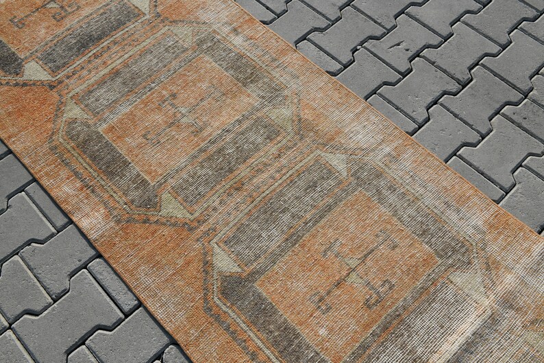 K&ouml;nnte beinhalten: Ein Vintage-L&auml;ufer mit geometrischem Muster in Braun-, Beige- und Wei&szlig;t&ouml;nen. Der Teppich hat einen Used-Look und ist perfekt, um jedem Raum einen Hauch von Boho-Stil zu verleihen.