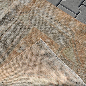 K&ouml;nnte beinhalten: Nahaufnahme eines gewebten Teppichs in beige, braun und grau. Der Teppich hat einen abgenutzten, Vintage-Look und ist aus Naturfasern gefertigt.