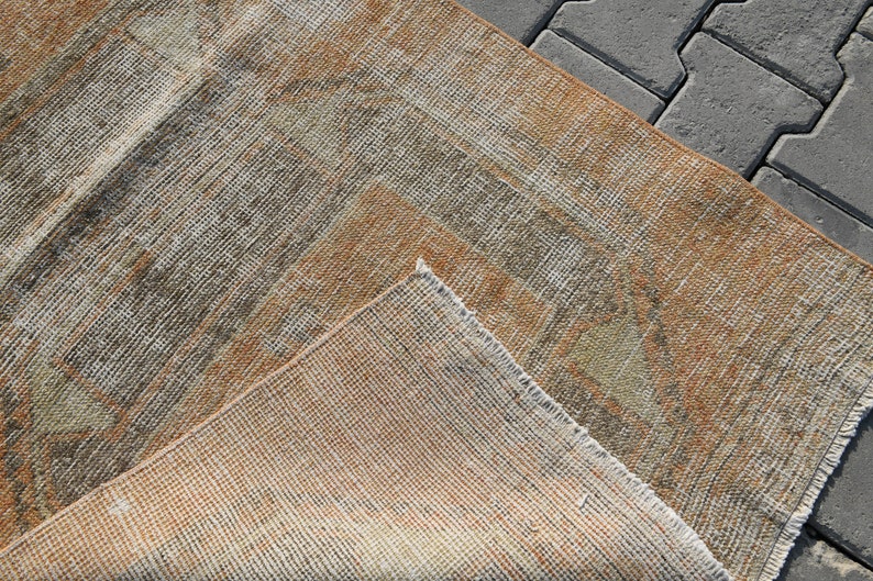 K&ouml;nnte beinhalten: Nahaufnahme eines gewebten Teppichs in beige, braun und grau. Der Teppich hat einen abgenutzten, Vintage-Look und ist aus Naturfasern gefertigt.
