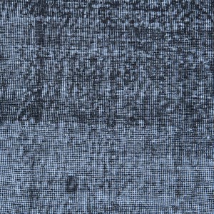 May include: A rectangular area rug featuring a dense, woven texture with a distressed aesthetic. The surface displays a mottled pattern of deep black and faded light gray tones, creating a high-contrast, weathered appearance across the entire fabric.